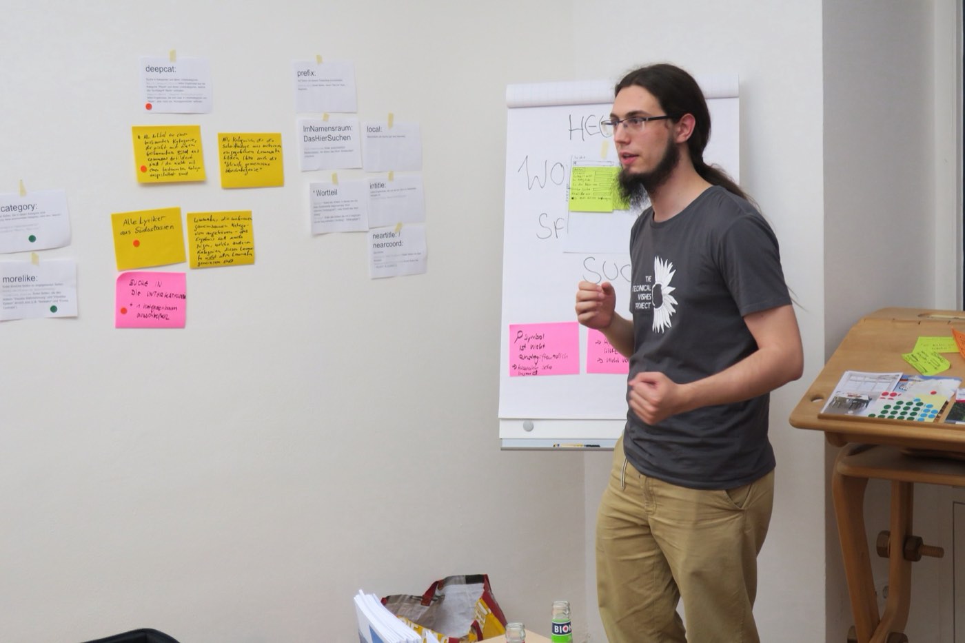 A facilitator leads a workshop in front of a wall of sticky notes